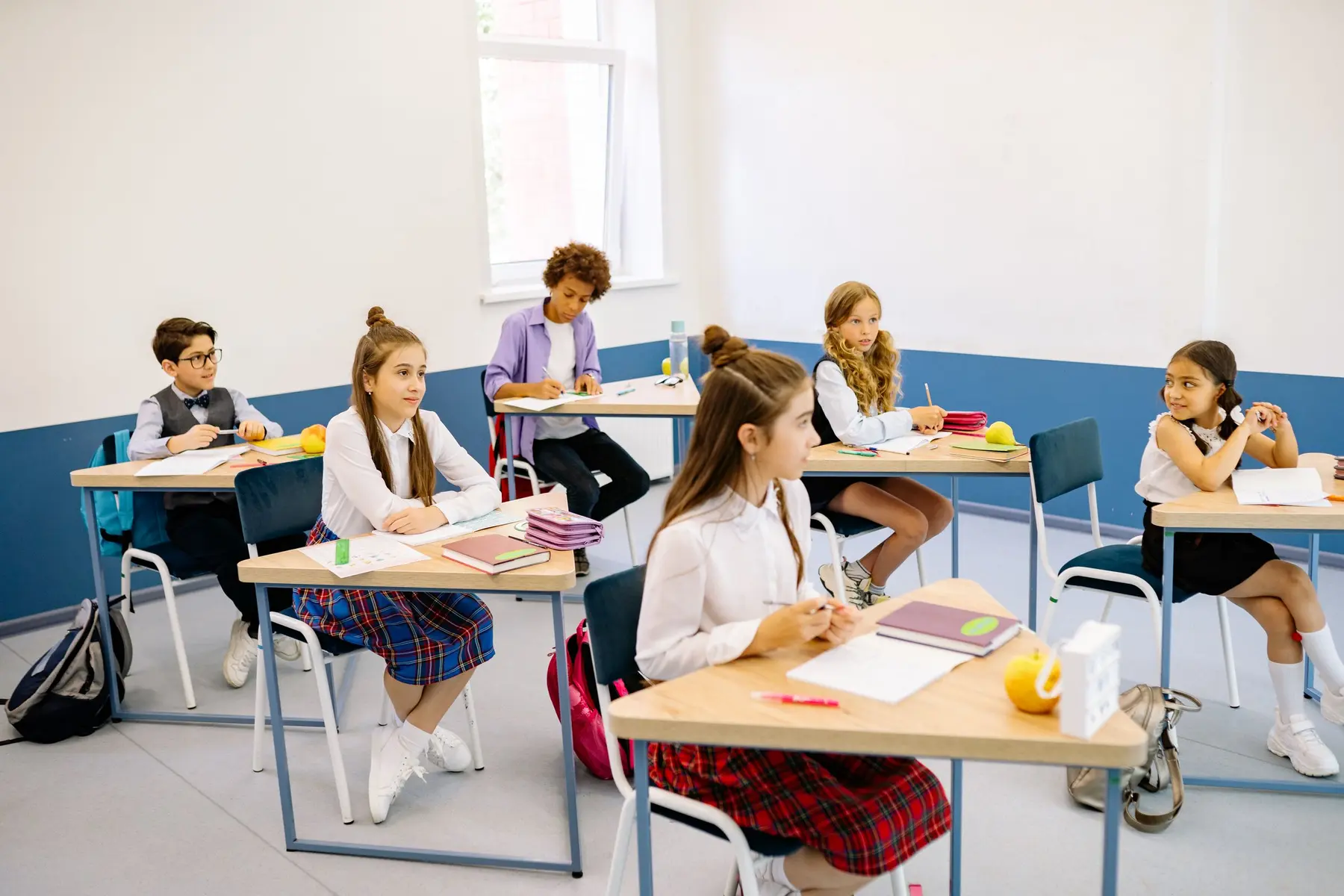 Pupils in uniform working at their desks in a bright classroom