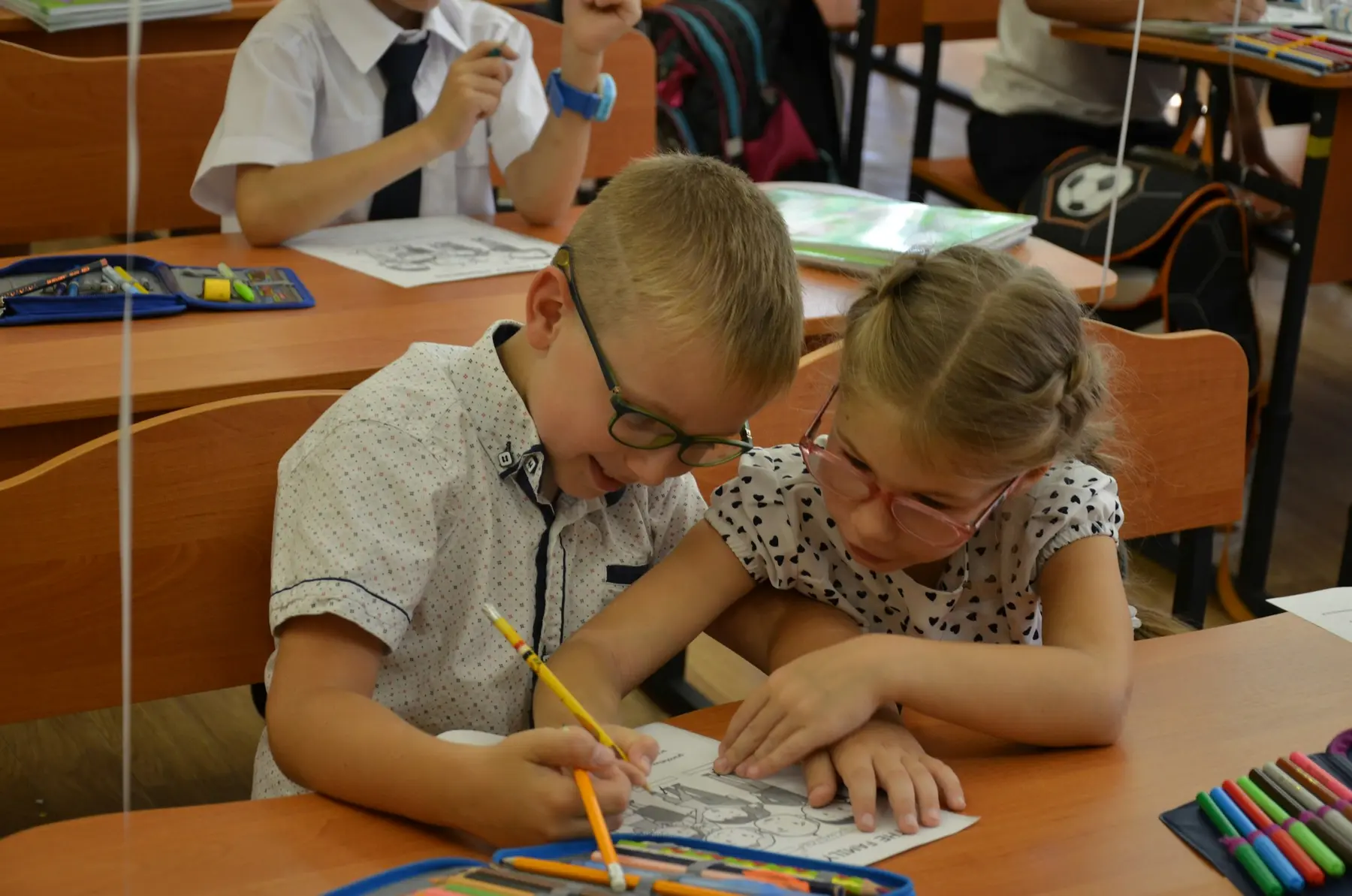 Two young pupils drawing together in class